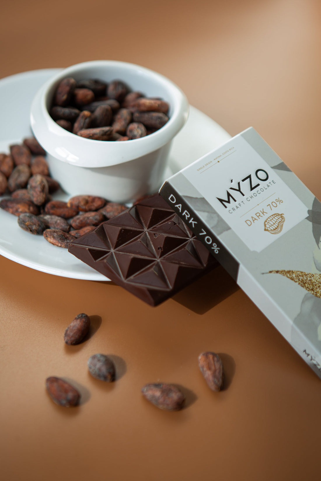 Myzo 70% Dark Chocolate with cacao beans on a saucer
