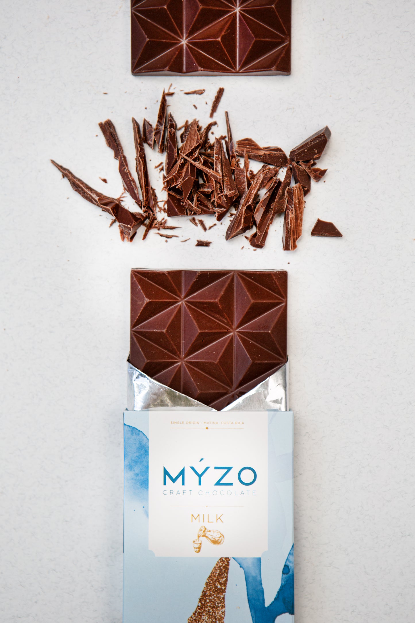 Close-up of MYZO milk chocolate bar broken into squares revealing creamy 48% single-origin texture