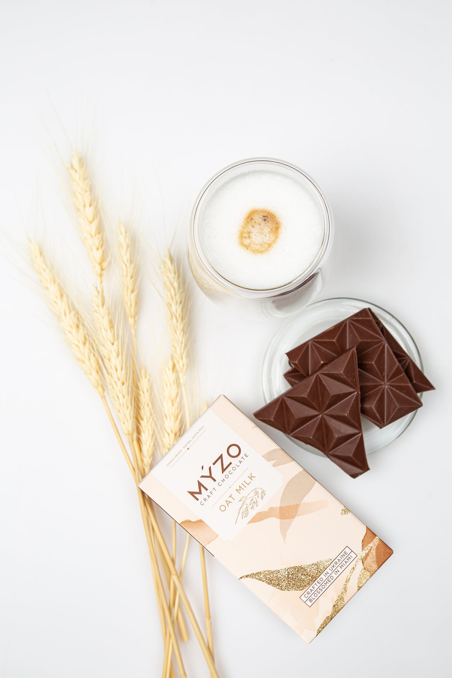 MYZO chocolate bars with a box, glass of milk, and wheat stalks on a white background