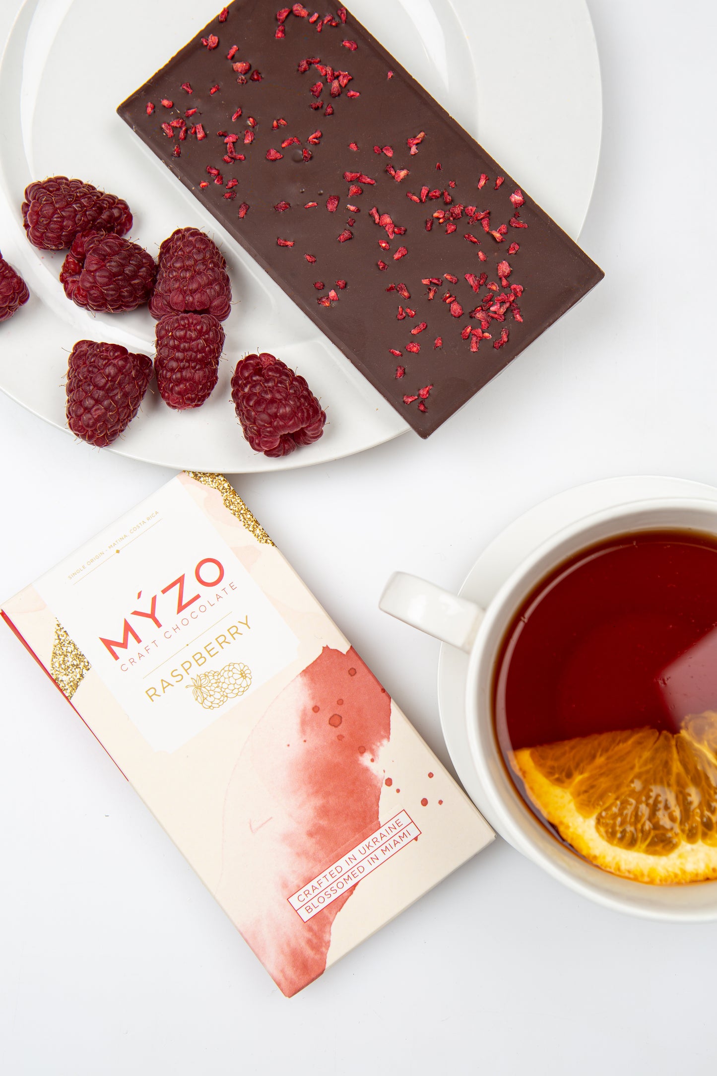 MYZO Raspberry Dark Chocolate styled with fresh berries and tea — single-origin Costa Rican cacao