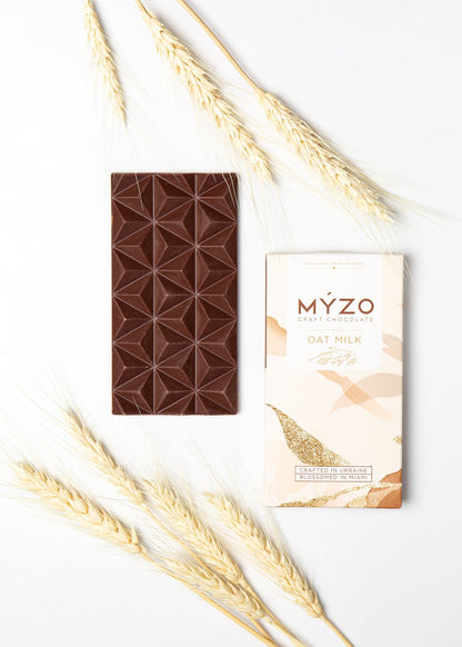 Flat lay of MYZO Oat Milk Chocolate bar with wrapper and natural oat-based ingredients