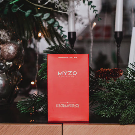 A 6-bar gift box of Myzo chocolates in with a pinetree reef in the background. Chocolates are being unpacked and broken in front of the viewer.