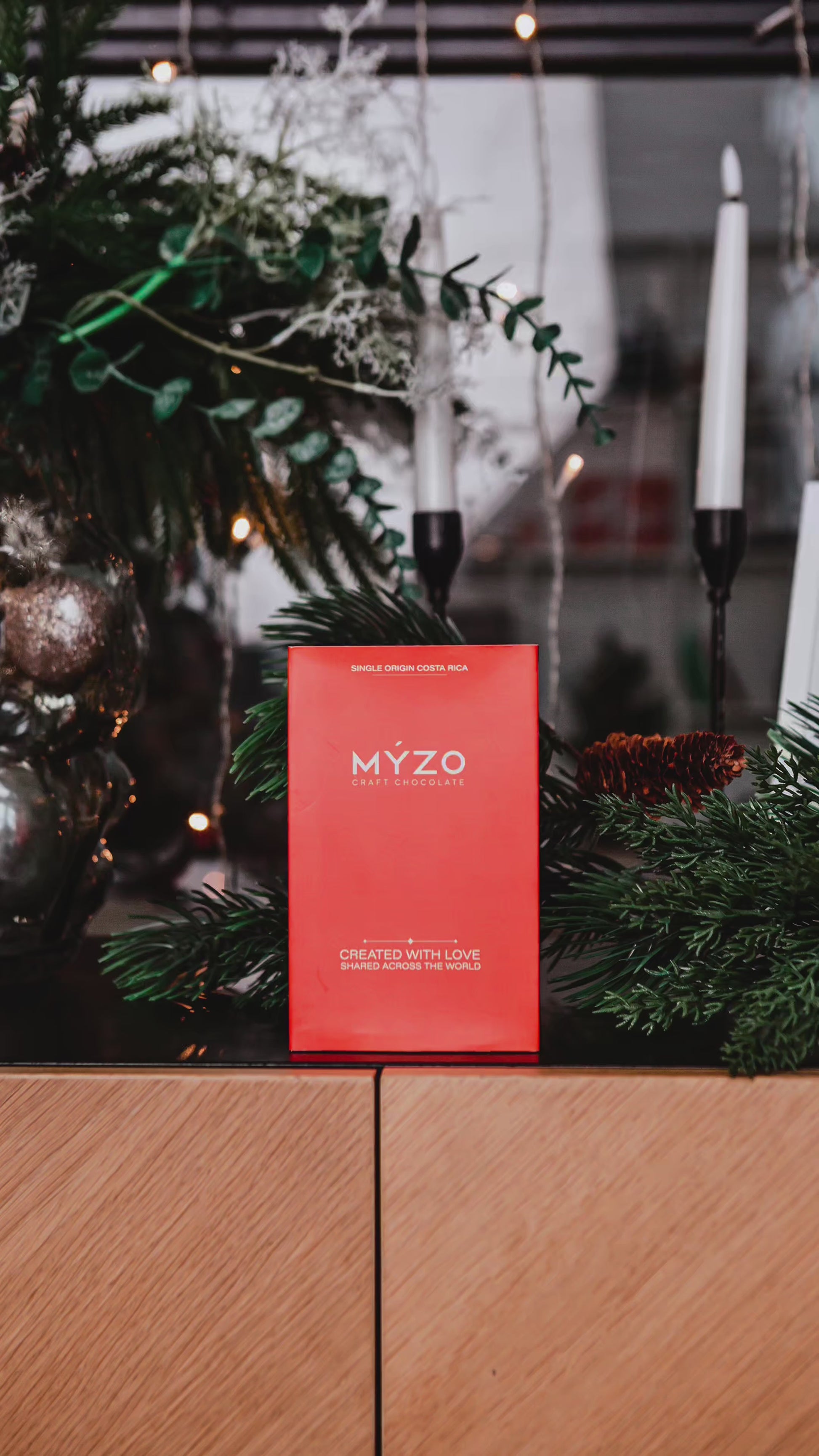 A 6-bar gift box of Myzo chocolates in with a pinetree reef in the background. Chocolates are being unpacked and broken in front of the viewer.